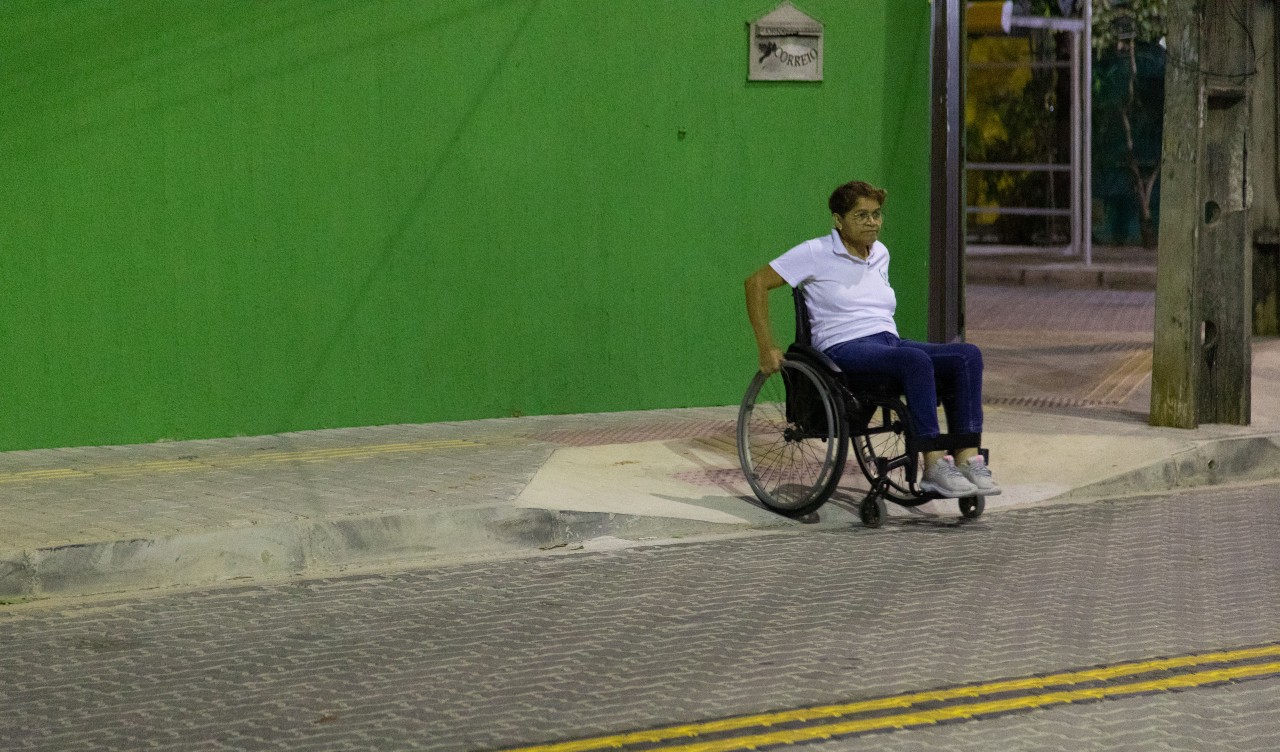 mulher cadeirante utiliza rampa de uma calçada para poder se locomover
